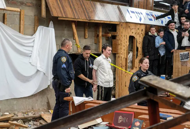 New York Police officers arrest a Hasidic Jewish student after he was removed from a breach in the wall of the synagogue that led to a tunnel dug by students