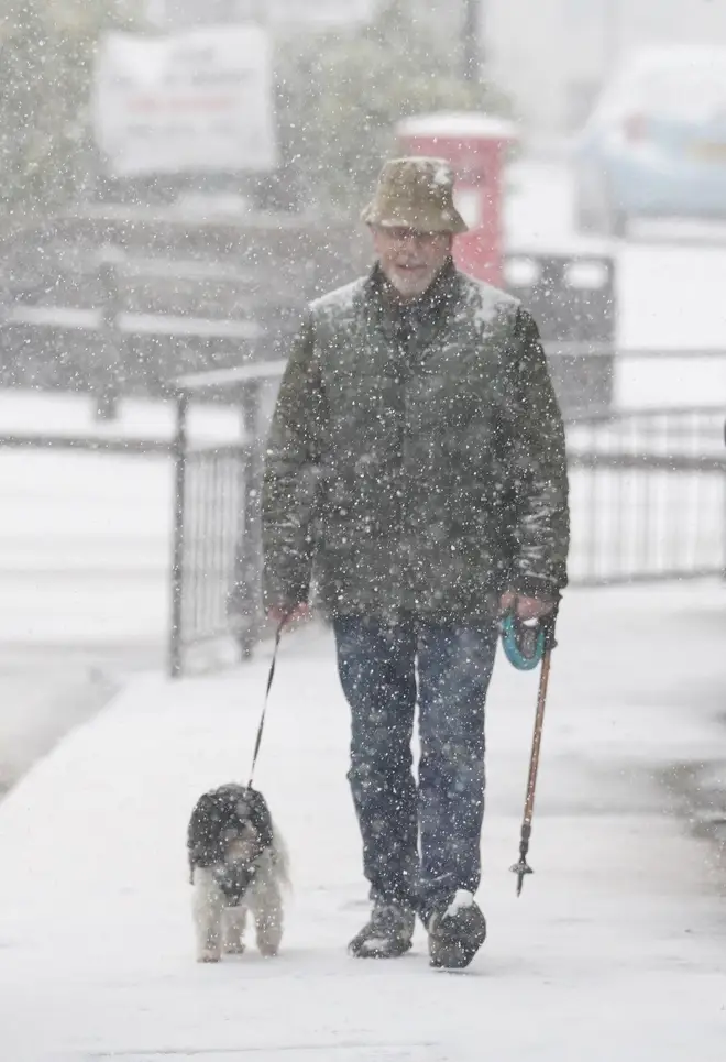 A man walks dog through a snow flurry in Lenham, Kent on Monday