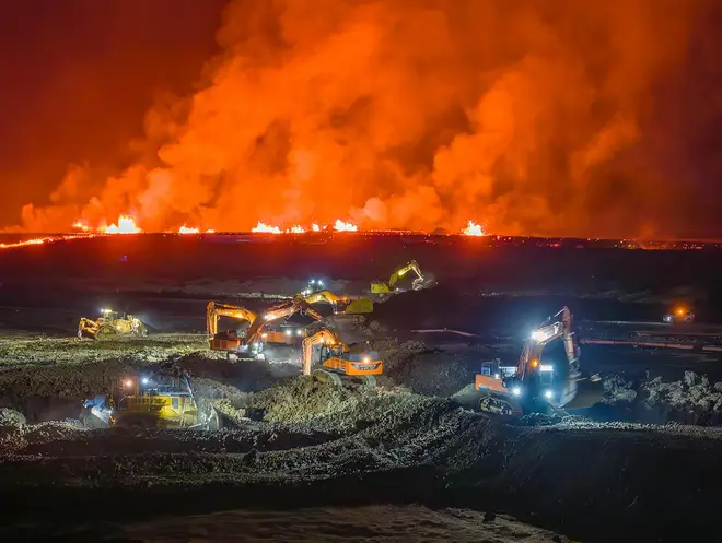 Diggers work through the night to form a barrier of defence against lava