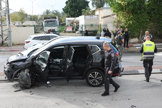 Israeli emergency and security personnel stand next to a damaged car following a suspected ramming attack in the central town of Raanana