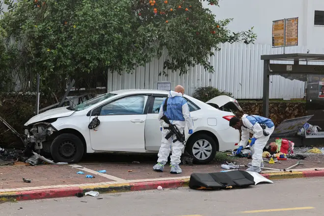Israeli police forensics personnel inspect a damaged car following a suspected ramming attack in the central town of Raanana