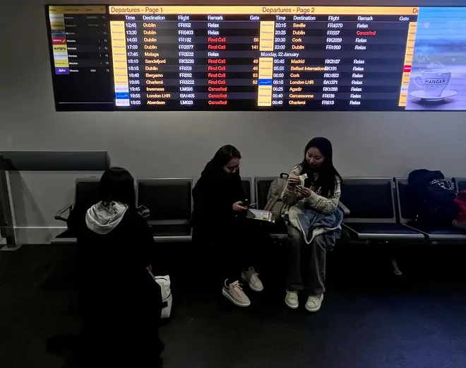 Passengers wait as departure boards at Manchester Airport show many flights cancelled or delayed due to high winds caused by Storm Isha