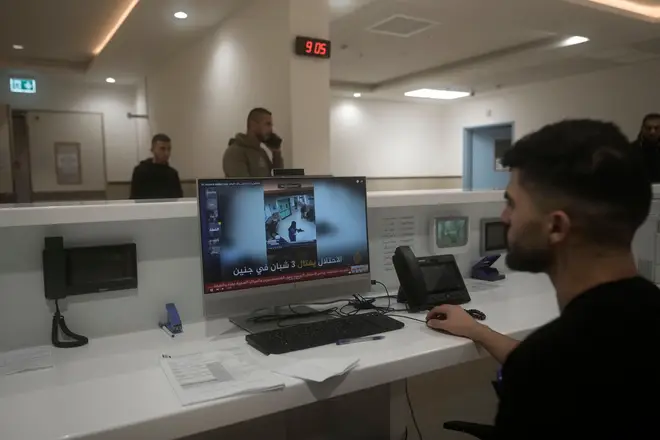 A staff member at Ibn Sina Hospital shows a news broadcast of security camera footage showing the raid