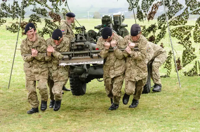 Soldiers from the Royal Artillery strain to pull a 105mm Light Artillery Gun