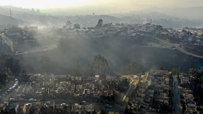 Smoke rises from burnt-out houses after a forest fire reached Villa Independencia neighbourhood in Vina del Mar, Chile