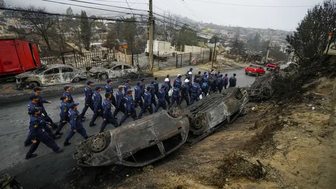 Navy personnel walk past overturned and charred cars in Chile