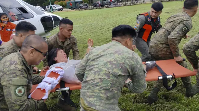 Soldiers carry a landslide victim as they arrive at Tagum City, Davao del Norte province, southern Philippines