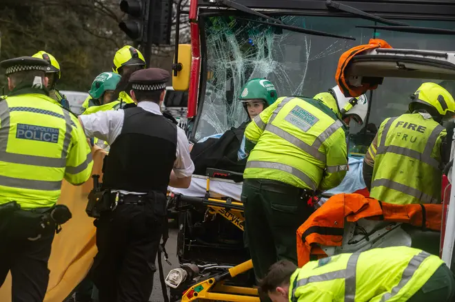 Fire and Rescue Service members work to recover a police officer trapped in a van after it was hit by a bus