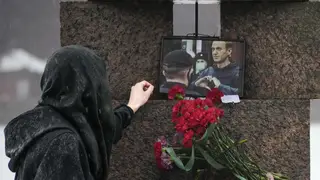 A woman touches a photo of Alexei Navalny after laying flowers paying the last respects to him at the Memorial to Victims of Political Repression in St Petersburg, Russia