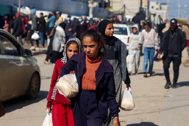 Palestinian girls carry fresh bread in Rafah, on the southern Gaza Strip on February 7, 2024