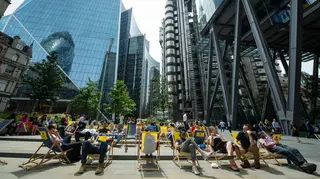 People sit on deckchairs near the Lloyds of London building, London, as more hot weather is due to hit the UK this week.