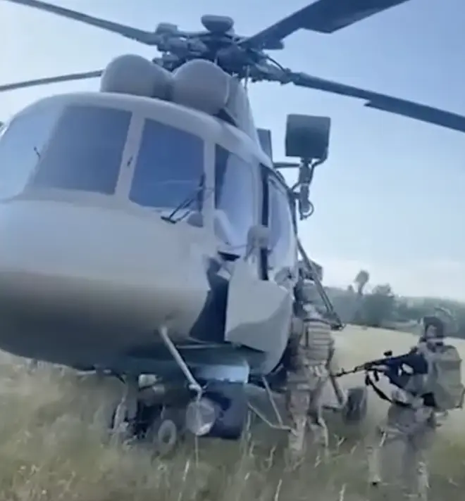 Ukrainian troops inspect a Russian helicopter which they say was handed over to Ukraine by Russian pilot Maksim Kuzminov