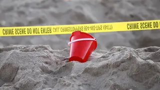 A bucket rests next to caution tape on a beach in Lauderdale-by-the-Sea, Florida