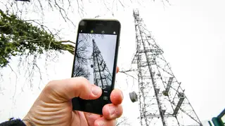 A mobile phone next to a telecoms mast