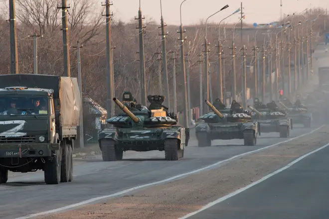 A column of tanks marked with the Z symbol stretches into the distance as they proceed northwards along the Mariupol-Donetsk highway