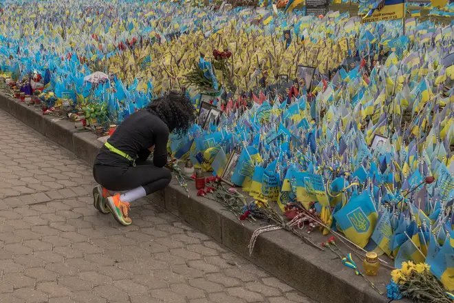 A woman next to flags bearing symbols and colours of Ukraine set to commemorate fallen Ukrainian army soldiers at Independence Square in Kyiv, on February 24, 2024, on the second anniversary of Russia's invasion