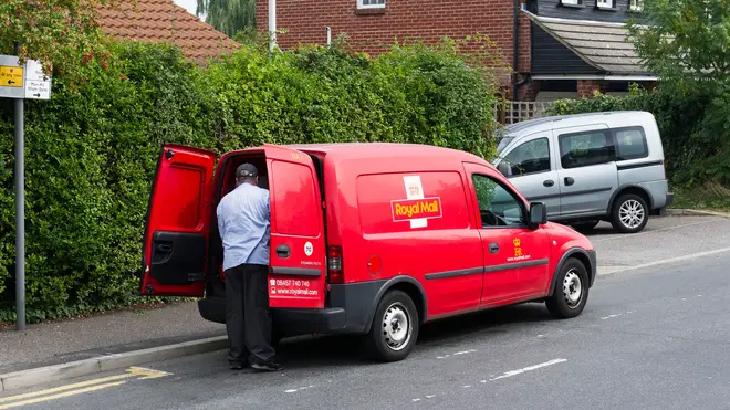 A Royal Mail worker emptying his van.