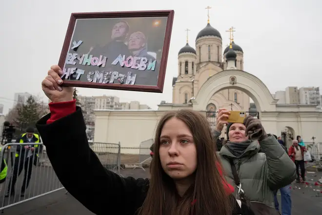 A woman holds a portrait of Alexei Navalny, left, and his wife Yulia, signed 'Eternal love has no death'