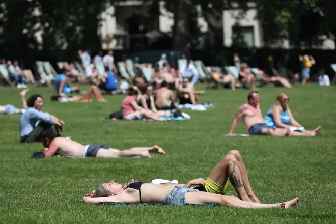 Sunbathers lie on the grass in Green Park, London.