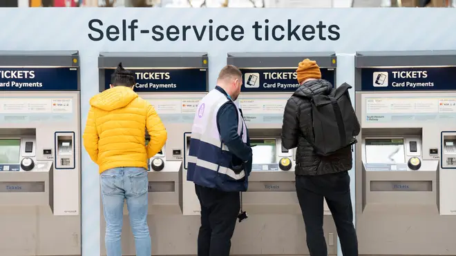 A member of staff assists a person at the ticket machines in Waterloo Station train station