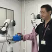 Dr Jihong Zhu testing out a robot dresser (University of York/PA)