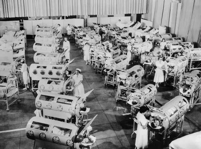 Nurse attend to a room full of polio patients in iron lung respirators