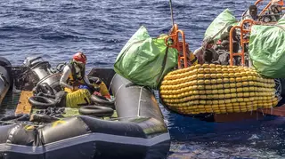 A migrant is helped to evacuate a partially deflated rubber dinghy in the Central Mediterranean Sea