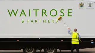 A worker cleans a Waitrose delivery lorry (PA)