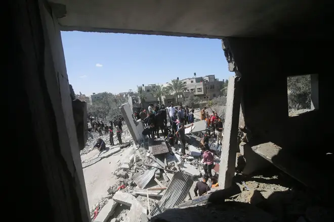 Palestinians look at a residential building destroyed in an Israeli strike in Rafah