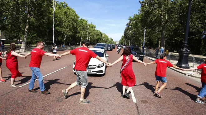 Greenpeace activists wearing sashes reading “Climate Emergency” held hands to form a human chain across The Mall stalling the incoming Prime Minister's journey to meet the Queen.