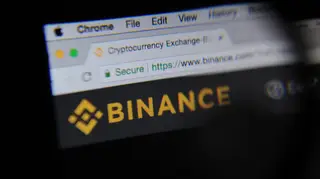 The cryptocurrency exchange website Binance is seen through a magnifying glass