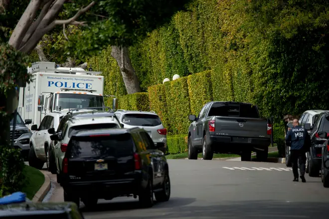 A federal investigator walks on a street in front of a LA property belonging to Sean "Diddy" Combs during the raids on his homes
