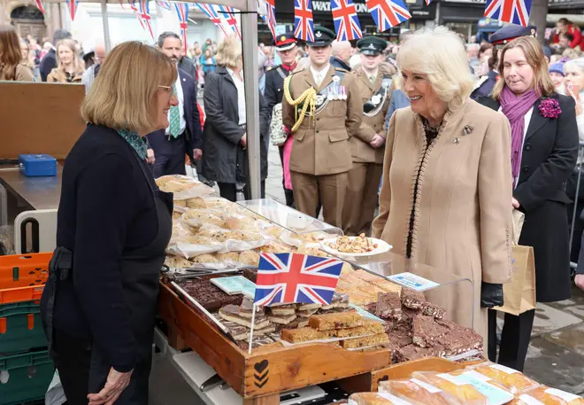 Queen Camilla greets a market trader during her visit to the Farmers' Market in Shrewsbury