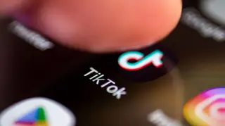 A person pressing on the Tik Tok logo on the screen of a smartphone