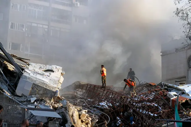 Emergency services work at a destroyed building hit by an air strike in Damascus, Syria, Monday