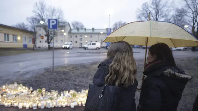 People bring candles and flowers at the school in Finland