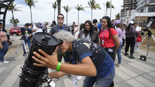 An amateur astronomer prepares her telescope a day before a total solar eclipse in Mazatlan, Mexico (Fernando Llano/AP)