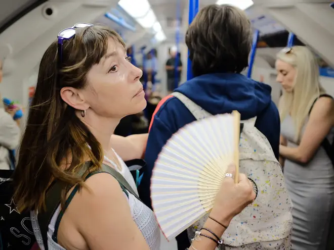 A woman uses a fan to cool down on a tube train in central London as the UK is expected to edge towards its hottest ever July day, with the mercury due to soar above 30C (86F).
