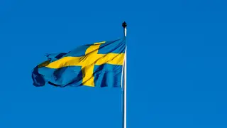 The Swedish flag fluttering in the breeze against a clear blue sky