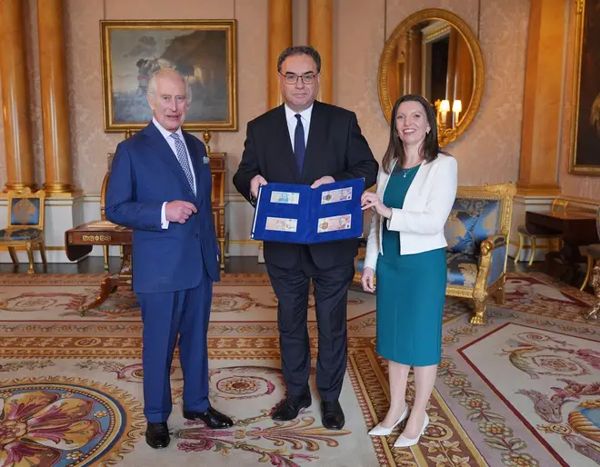 King Charles III (left) is presented with the first bank notes featuring his portrait from the Bank of England Governor Andrew Bailey (centre) and Bank of England's Chief Cashier Sarah John, at Buckingham Palace.