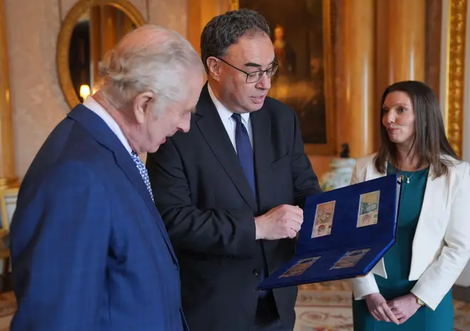 King Charles III (left) is presented with the first banknotes featuring his portrait from the Bank of England Governor Andrew Bailey and Sarah John, the Bank of England's Chief Cashier.