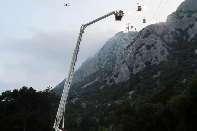A rescue team work with passengers of a cable car transportation system outside Antalya, southern Turkey, Friday