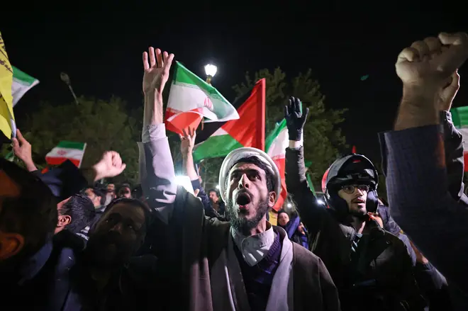 Demonstrators wave Iran and Palestinian flags as they gather in front of the British Embassy in Tehran
