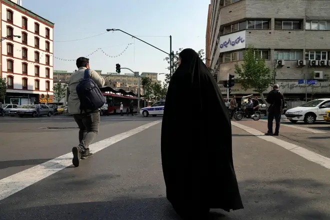 People cross a road in Tehran, Iran, Sunday, April 14