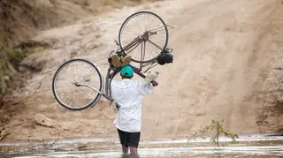 A man carries a bike through floodwater