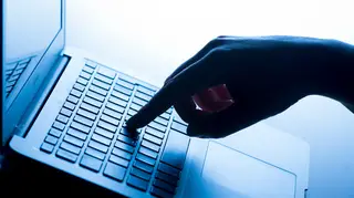 A woman’s hand presses a key of a laptop keyboard
