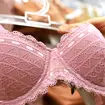 Pink lace bra on a rack in female hand in lingerie store