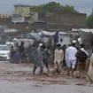 People wade through floodwater in Peshawar