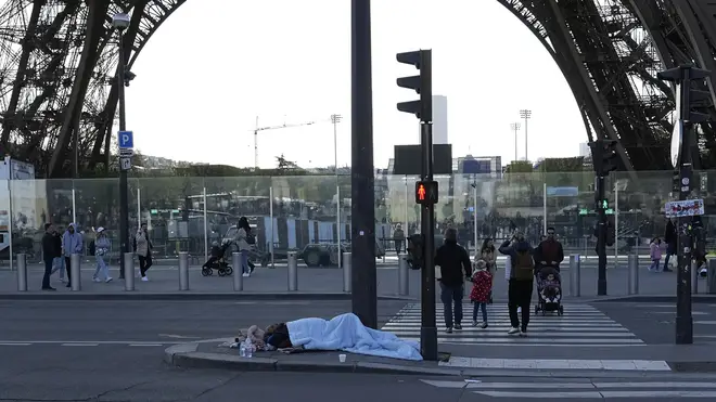 A homeless person sleeps near the Eiffel Tower