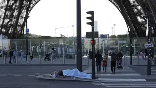 A homeless person sleeps near the Eiffel Tower